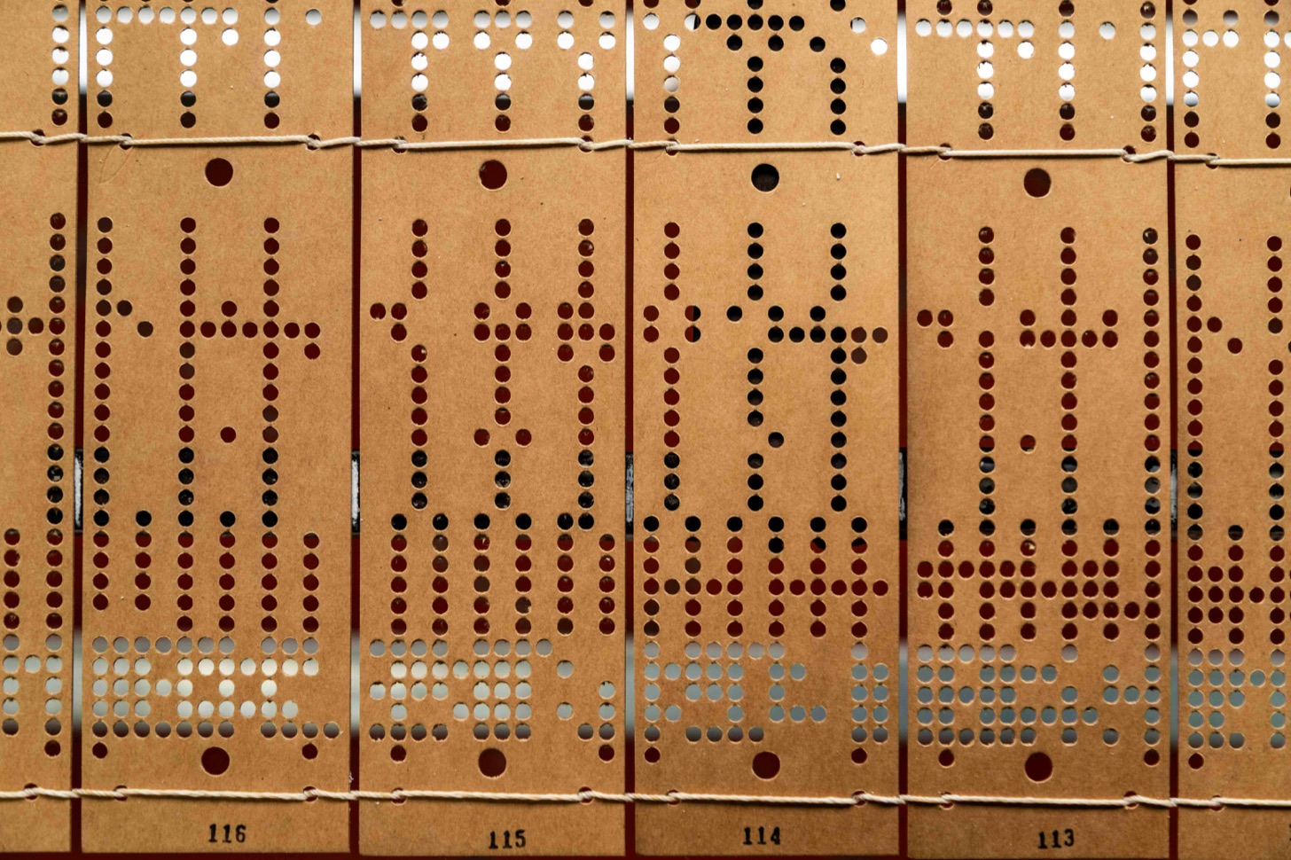 Rows of vintage punched cards filled with rectangular data holes.